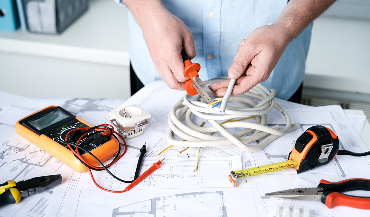 Man,repairer making electricity project in house.Repairs planning.Drawings,diagrams,plan for electrification of apartment,building.Devices,accessories,voltmeter,wires,screwdriver,pliers,tape measure